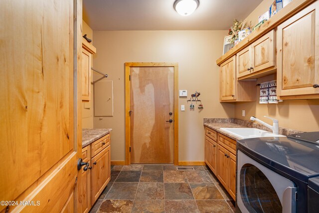 laundry room with sink, washer and clothes dryer, and cabinets