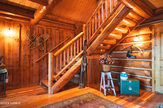 stairs with wooden ceiling, hardwood / wood-style floors, log walls, and beamed ceiling