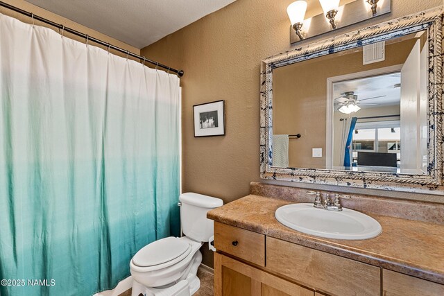 full bathroom featuring a textured wall, toilet, ceiling fan, vanity, and curtained shower