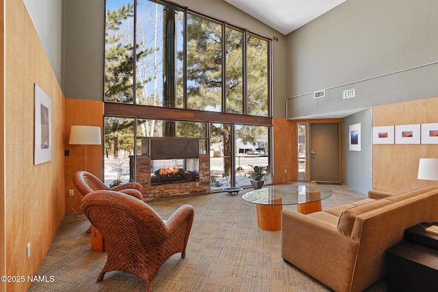 living room with a towering ceiling, healthy amount of natural light, and a multi sided fireplace