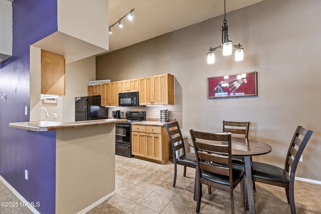 kitchen featuring black appliances, baseboards, light brown cabinetry, rail lighting, and a high ceiling