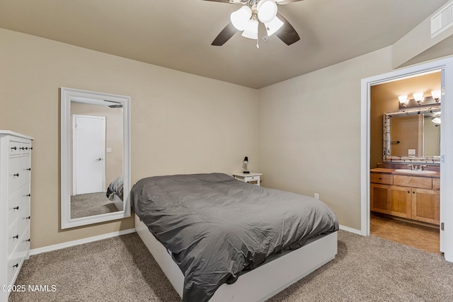 bedroom with a sink, light colored carpet, baseboards, ensuite bathroom, and a ceiling fan