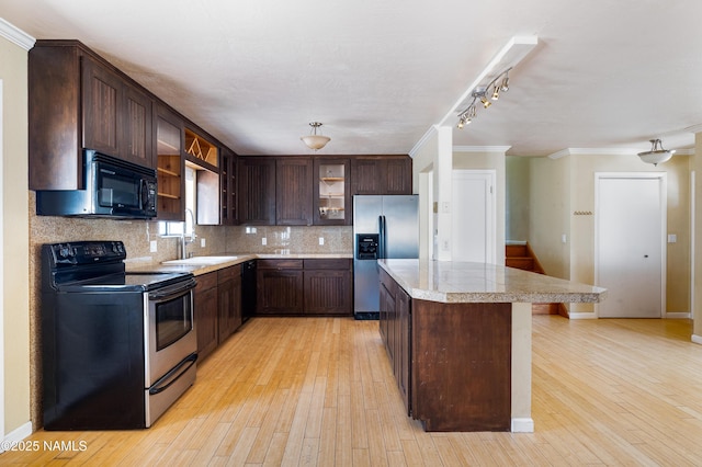 kitchen featuring dark brown cabinetry, tasteful backsplash, a center island, black appliances, and a sink