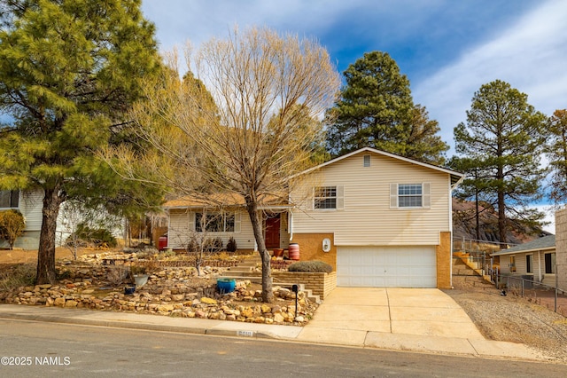 split level home with concrete driveway, an attached garage, and fence