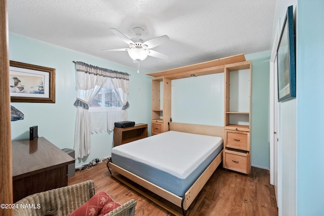 bedroom with ceiling fan, dark wood-type flooring, and a textured ceiling