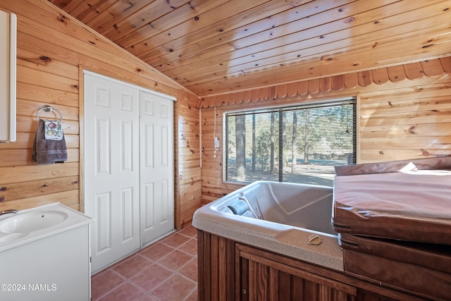 bathroom with tile patterned flooring, a bath, wooden ceiling, and wood walls