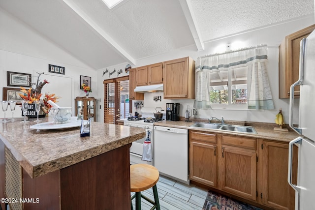 kitchen featuring sink, white appliances, plenty of natural light, lofted ceiling with beams, and a textured ceiling