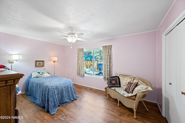 bedroom with wood-type flooring, a textured ceiling, ceiling fan, and a closet