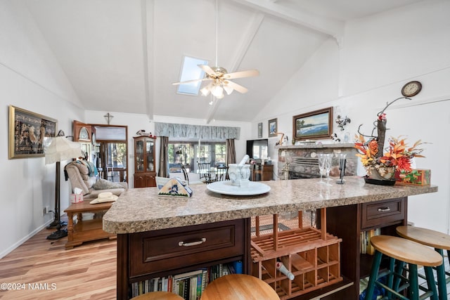 kitchen with beamed ceiling, dark brown cabinets, ceiling fan, and light hardwood / wood-style flooring