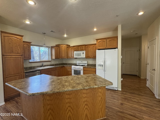 kitchen featuring sink, decorative light fixtures, dark hardwood / wood-style floors, a kitchen island, and white appliances