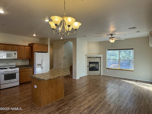 kitchen featuring a tile fireplace, decorative light fixtures, a center island, dark wood-type flooring, and white appliances