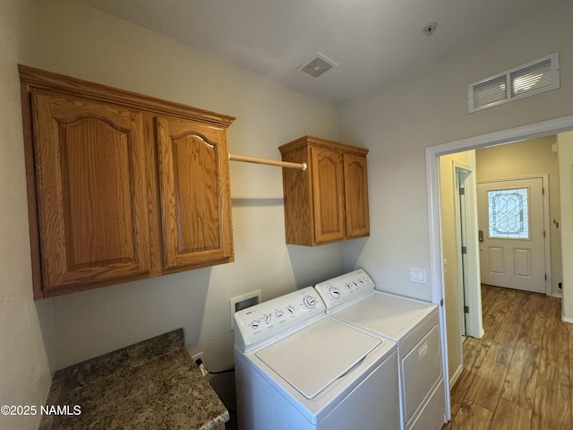 washroom featuring cabinets, light hardwood / wood-style floors, and washer and dryer