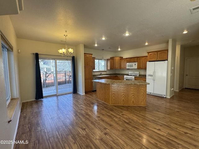 kitchen featuring pendant lighting, white appliances, an inviting chandelier, dark hardwood / wood-style floors, and a center island