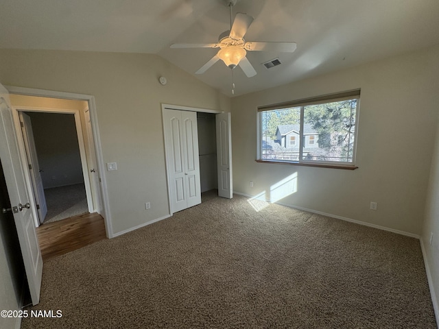 unfurnished bedroom featuring lofted ceiling, carpet flooring, ceiling fan, and a closet