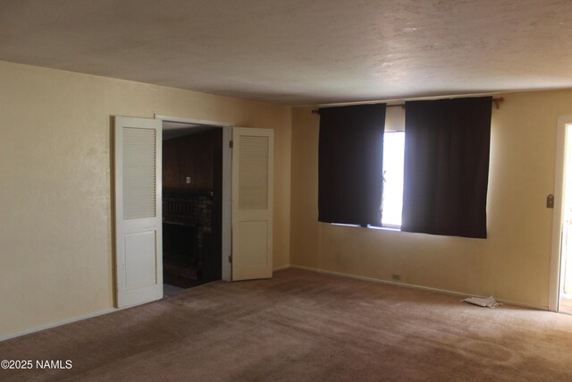 322 W Mahoney St, Winslow, AZ 86047 - empty room featuring carpet floors, a fireplace, and baseboards