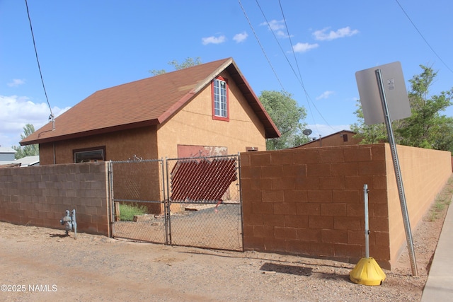 322 W Mahoney St, Winslow, AZ 86047 - view of home's exterior with a gate, stucco siding, a shingled roof, and fence