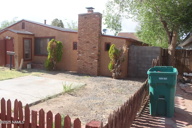 322 W Mahoney St, Winslow, AZ 86047 - view of property exterior with a chimney, stucco siding, and a patio area
