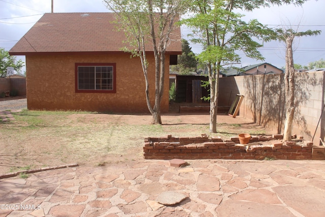 322 W Mahoney St, Winslow, AZ 86047 - rear view of house with fence, stucco siding, roof with shingles, and a patio area
