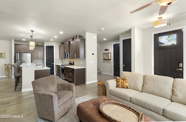 living room featuring ceiling fan, sink, and wood-type flooring