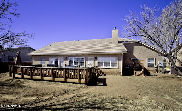 rear view of property featuring a deck, a tile roof, a chimney, and stucco siding