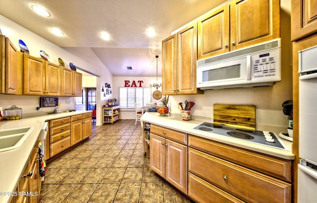 kitchen featuring brown cabinets, light countertops, vaulted ceiling, a sink, and white appliances