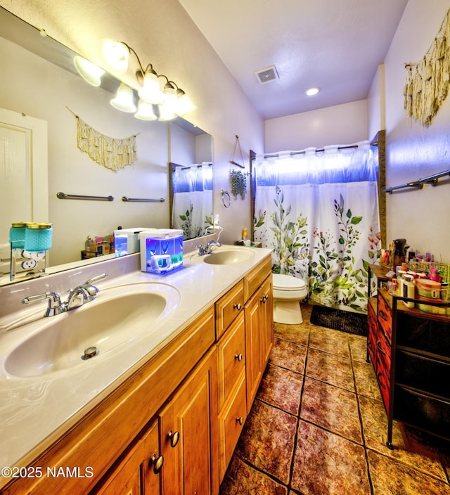 bathroom featuring toilet, visible vents, a sink, and tile patterned floors