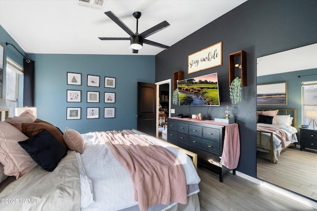 bedroom with ceiling fan, hardwood / wood-style flooring, and vaulted ceiling