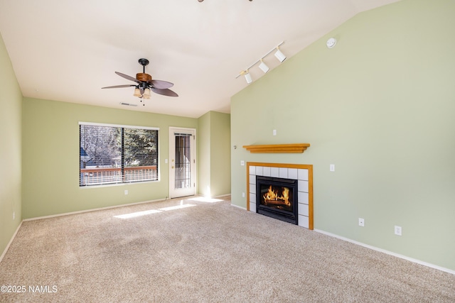 unfurnished living room featuring a fireplace, rail lighting, carpet, ceiling fan, and lofted ceiling