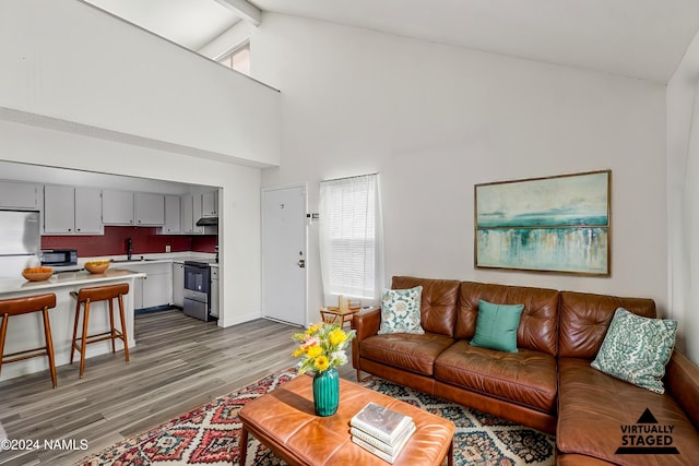 living room with sink, hardwood / wood-style flooring, high vaulted ceiling, and beam ceiling