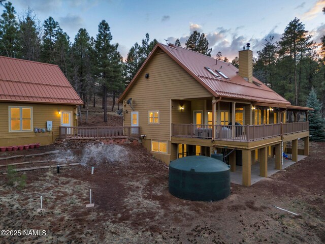 284 E Foothill Trl, Williams, AZ 86046 - back of house at dusk with a wooden deck, a standing seam roof, a chimney, and metal roof