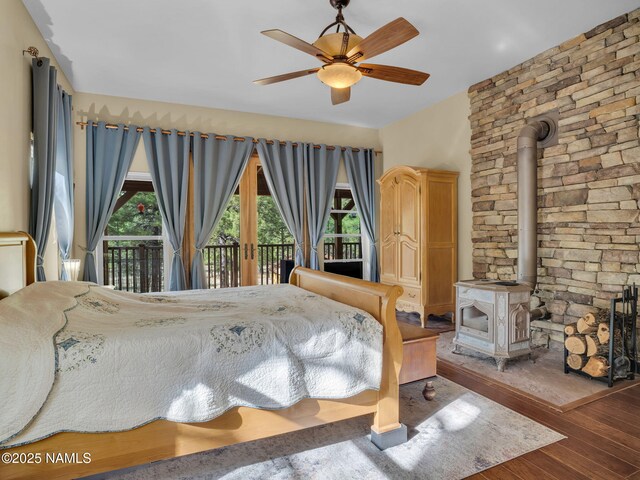 284 E Foothill Trl, Williams, AZ 86046 - bedroom with access to outside, a ceiling fan, a wood stove, and hardwood / wood-style floors