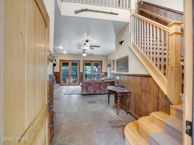 284 E Foothill Trl, Williams, AZ 86046 - living room with wood walls, stone finish floor, a wainscoted wall, a ceiling fan, and stairway