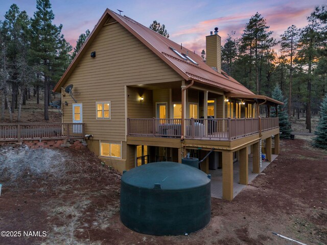 284 E Foothill Trl, Williams, AZ 86046 - back of property at dusk with a wooden deck, a chimney, and metal roof