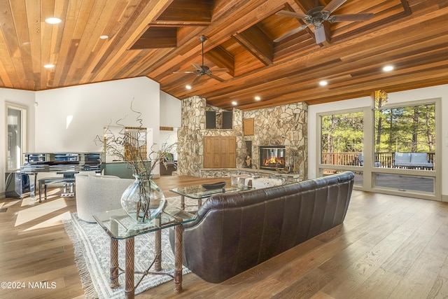 living room with vaulted ceiling with beams, a fireplace, ceiling fan, wooden ceiling, and light hardwood / wood-style flooring