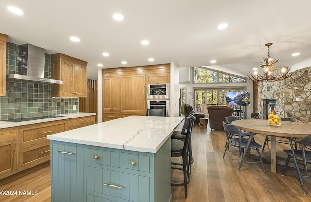 kitchen featuring decorative light fixtures, wall chimney range hood, black electric stovetop, tasteful backsplash, and a large island