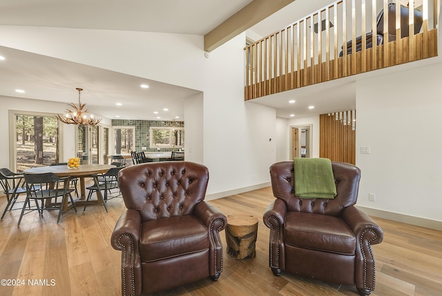 living room featuring a chandelier, light hardwood / wood-style floors, and lofted ceiling with beams