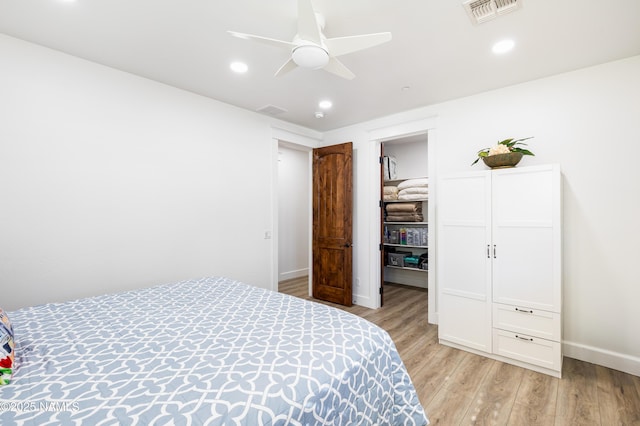 bedroom featuring ceiling fan, light wood-type flooring, a walk in closet, and a closet