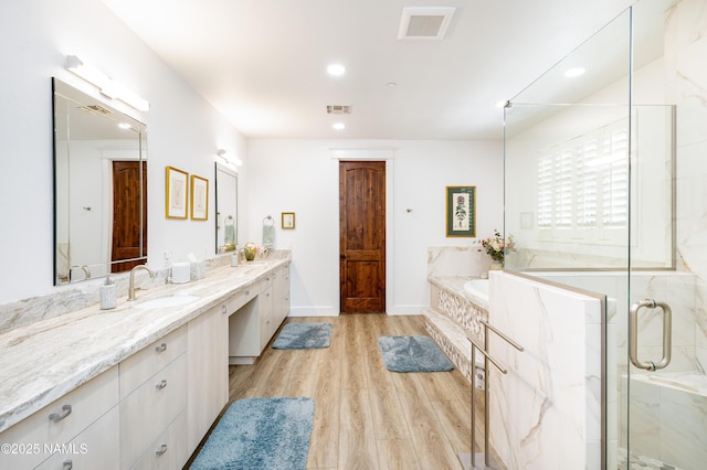 bathroom featuring plus walk in shower, vanity, and wood-type flooring