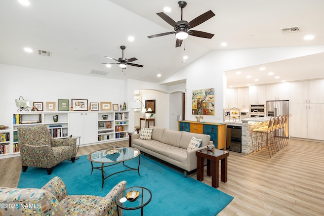 living room with high vaulted ceiling, light wood-type flooring, and beverage cooler