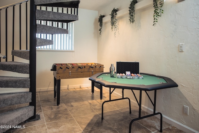 recreation room with baseboards and a textured wall