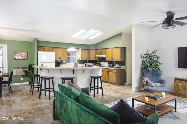 living area featuring vaulted ceiling with skylight and baseboards