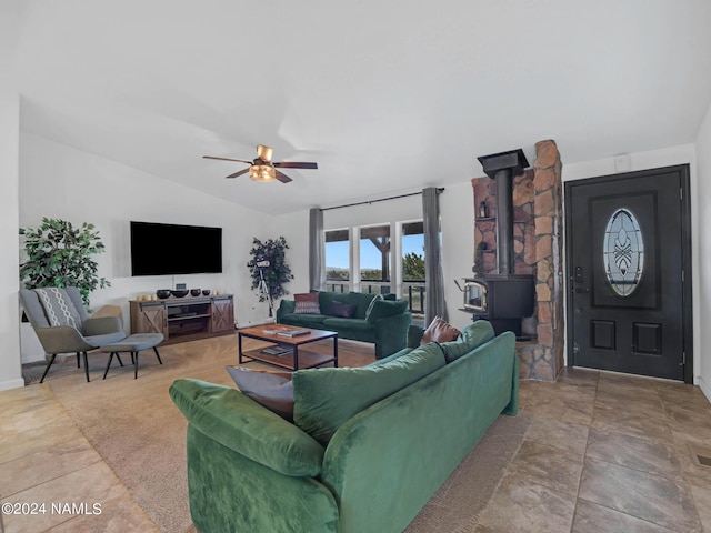 living area featuring a ceiling fan, a wood stove, and vaulted ceiling