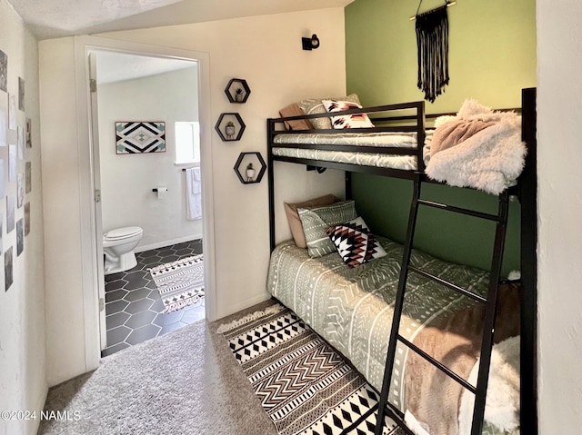 bedroom with carpet, connected bathroom, and baseboards