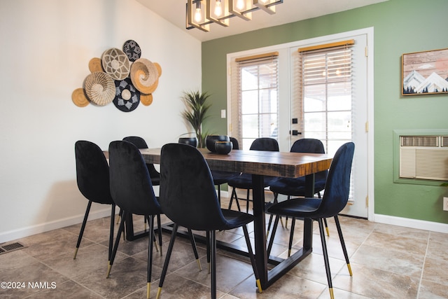 tiled dining space with baseboards, a wall mounted AC, visible vents, and an inviting chandelier