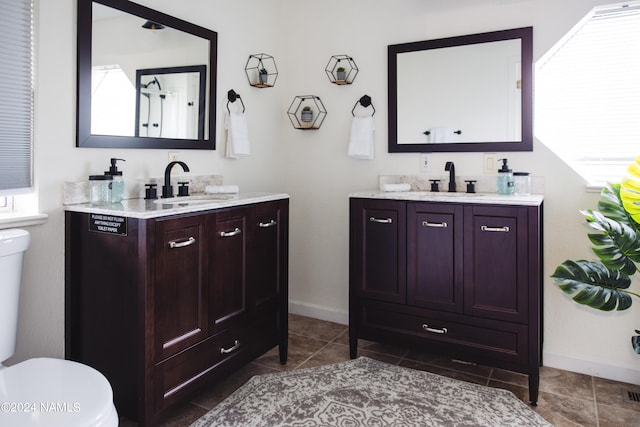 full bathroom featuring two vanities, a sink, and toilet