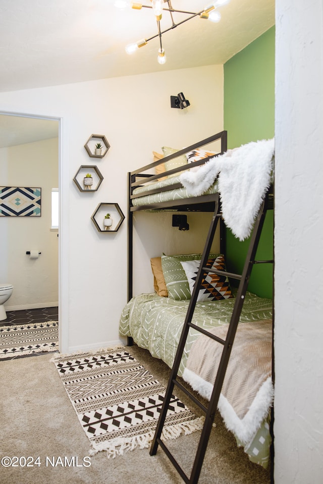 carpeted bedroom featuring a chandelier and connected bathroom