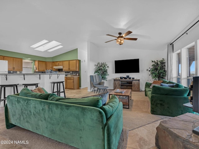 living area with ceiling fan, lofted ceiling with skylight, and light carpet