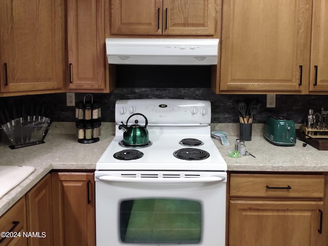 kitchen with brown cabinetry, range hood, electric stove, and light countertops