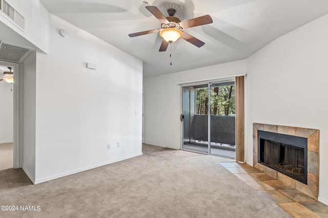 unfurnished living room with a tiled fireplace, light colored carpet, vaulted ceiling, and ceiling fan