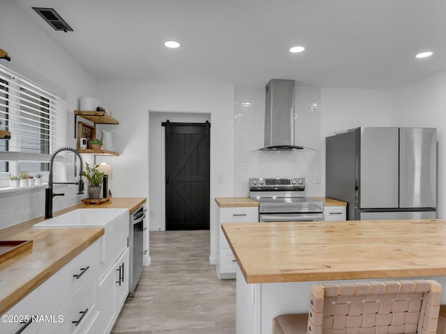 389 N Laramy Ln, Parks, AZ 86018 - kitchen featuring wooden counters, appliances with stainless steel finishes, a barn door, wall chimney exhaust hood, and recessed lighting